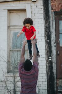 family mental health covid black dad tossing happy child into the air