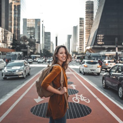 Young woman with backpack, ready to travel, standing in city street